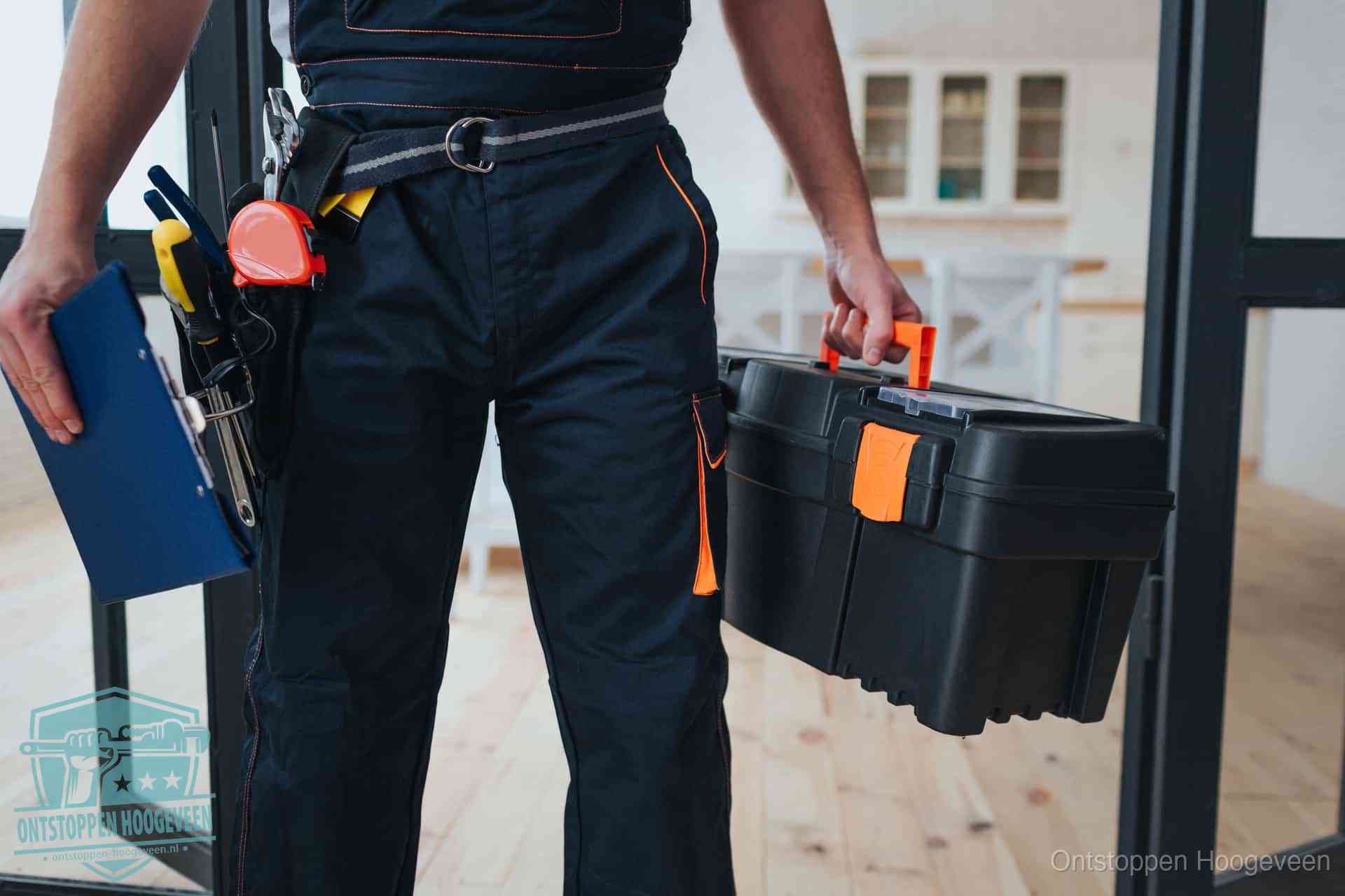 Een monteur met gereedschapsriem en klembord in een keuken, klaar om een transparante prijs voor het gootsteen ontstoppen in Hoogeveen te geven
