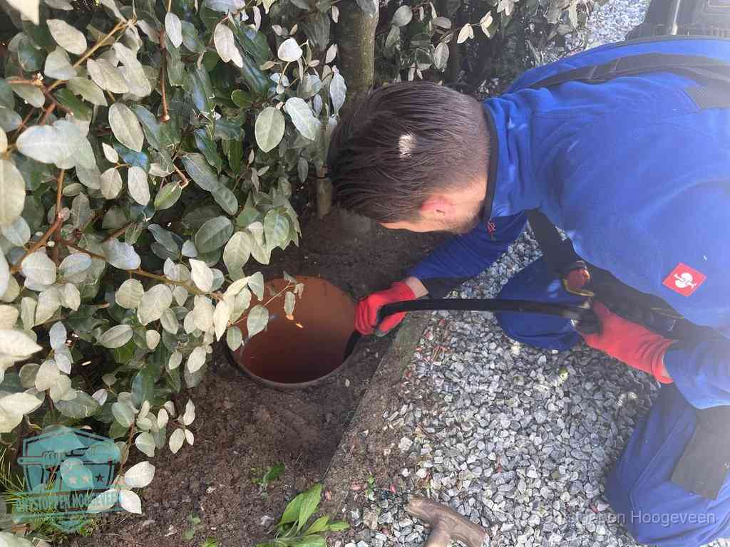 Monteur reinigt een rioolput met een slang, periodieke rioolreiniging in Hoogeveen