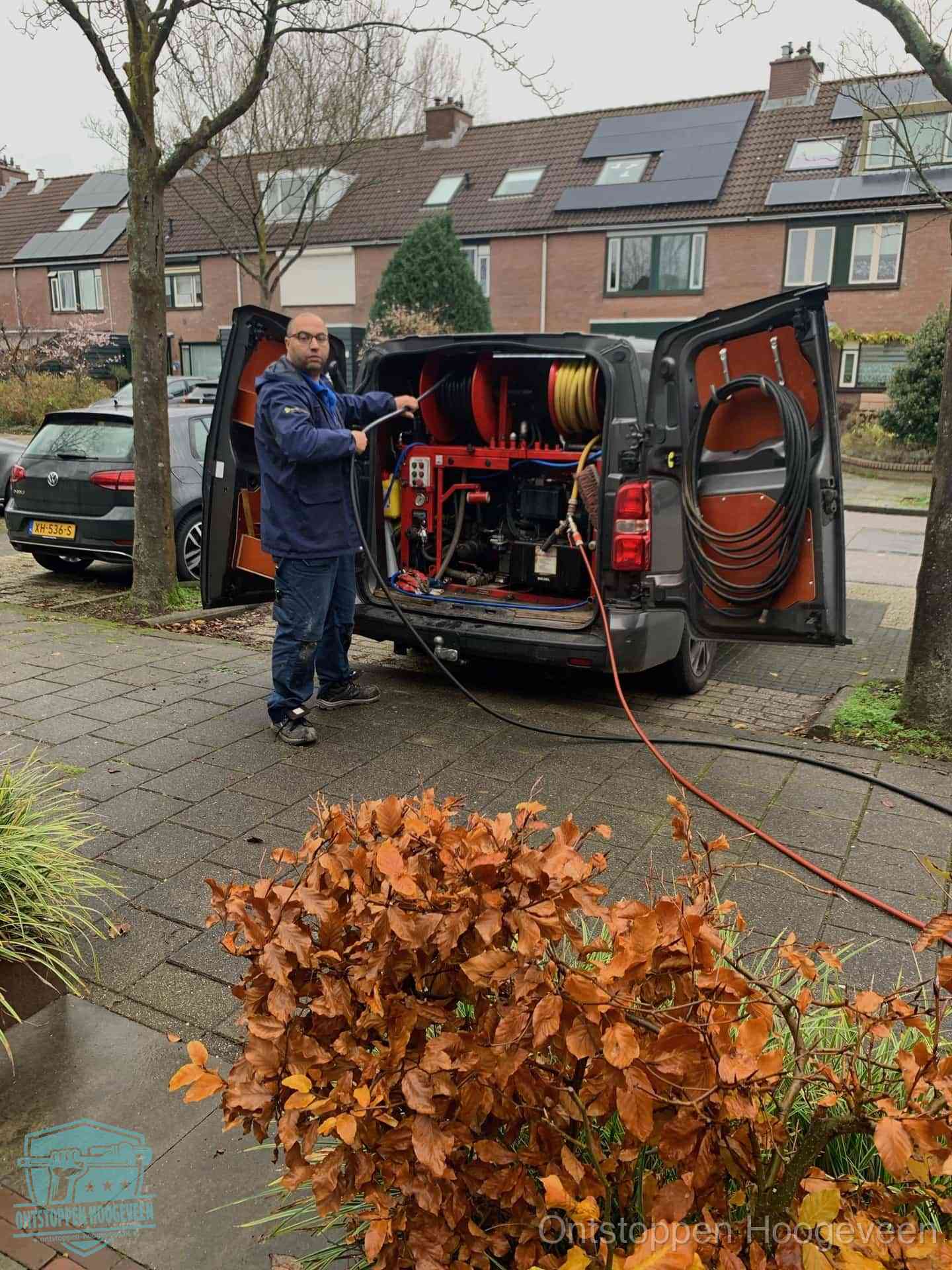 Monteur met rioolreinigingsbus levert rioolservice in de wijk in Hoogeveen
