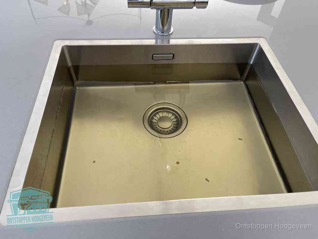 Stilstaand water in een rvs spoelbak dat niet wegloopt, een duidelijk signaal van een gootsteenverstopping in Hoogeveen