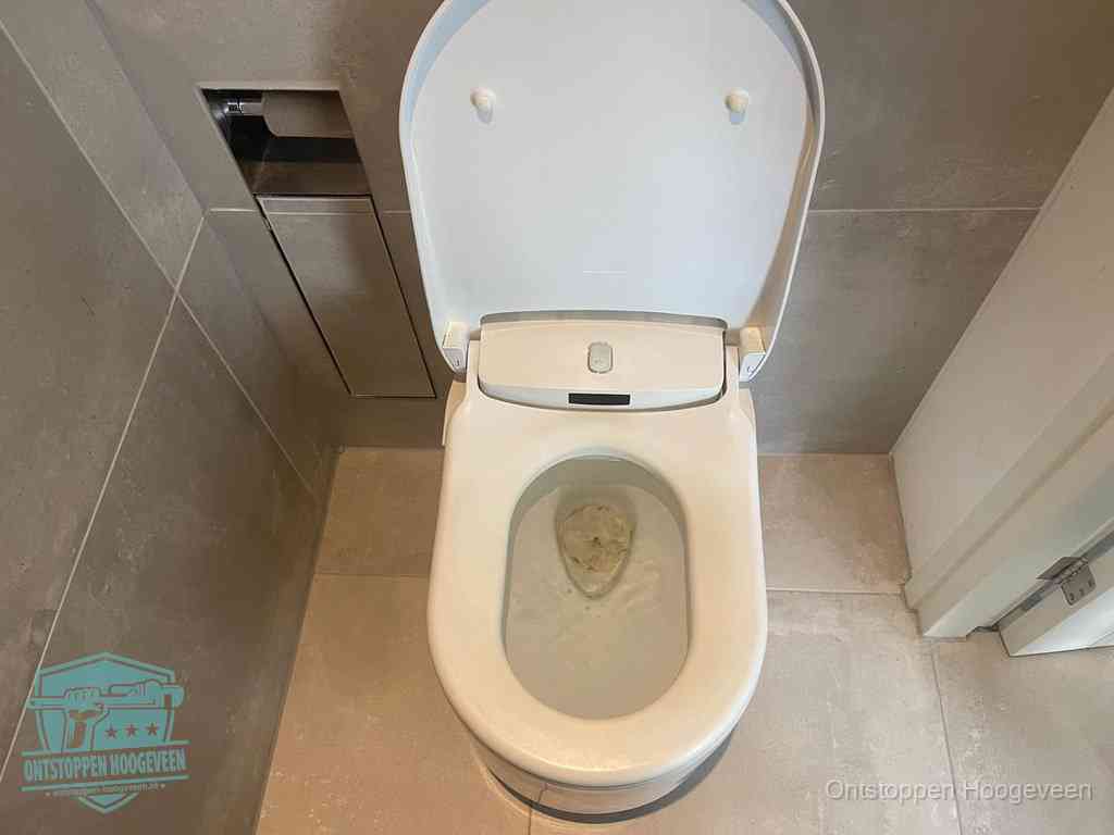 Een wit hangtoilet waarin een prop wc-papier op het water blijft drijven, een duidelijk signaal van een verstopte wc in Hoogeveen