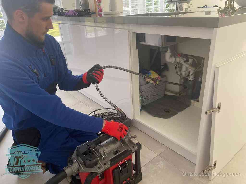 Een monteur reinigt de keukenafvoer grondig met een veermachine om terugkerende gootsteenverstoppingen te voorkomen in Hoogeveen