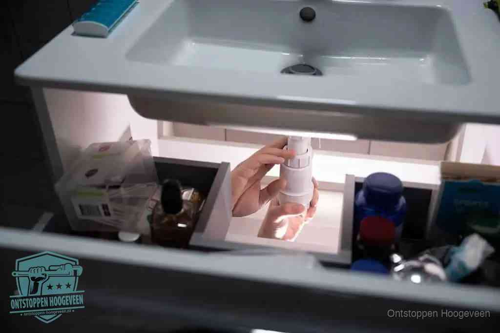 Een pompfles met zeep boven een wastafel in de toiletruimte, de warm water en afwasmiddel-methode om de wc te ontstoppen in Hoogeveen
