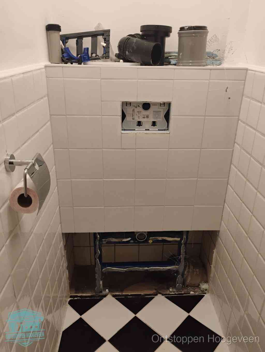 Een toiletruimte waar het hangtoilet en de inbouwreservoir-onderdelen zijn vrijgelegd voor onderhoud, periodiek nazicht voorkomt een wc-verstopping in Hoogeveen